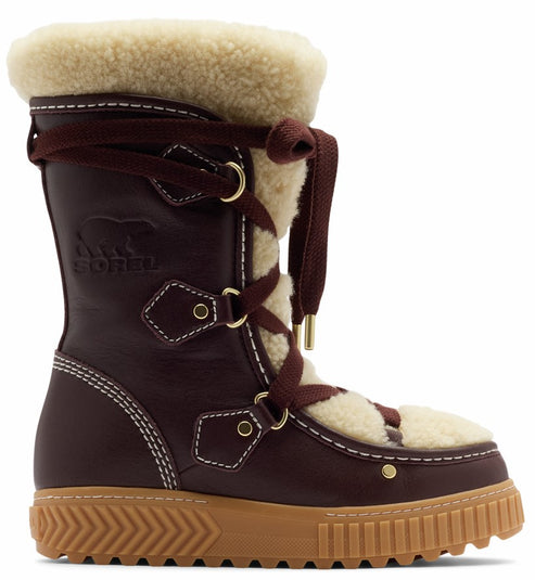A brown leather winter boot featuring cream-colored faux fur lining at the top and tongue, a lace-up front with gold-tone hardware, and a textured tan rubber lug sole. The SOREL logo is embossed on the side of the shaft.