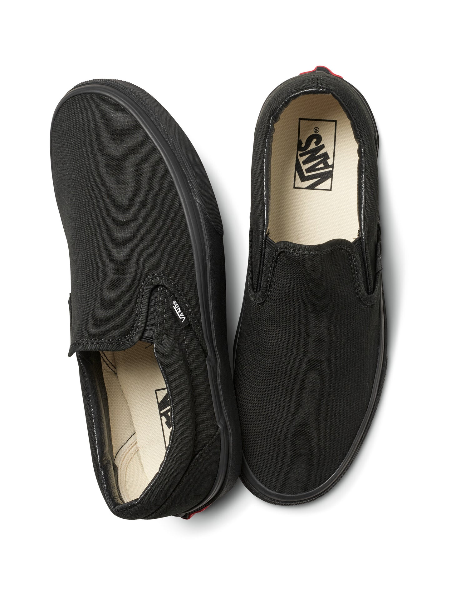 A pair of plain black slip-on shoes seen from above.