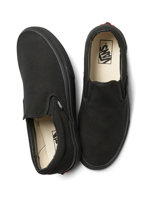 A pair of plain black slip-on shoes seen from above.