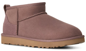 A dusty rose colored ankle boot with a flat, light brown rubber sole and a pull tab on the back.