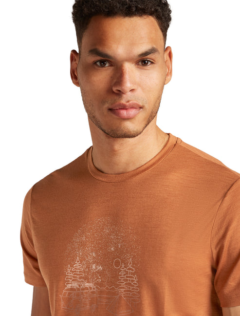 Man wearing an orange t-shirt with an illustrated landscape.