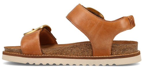 Tan leather sandal with a large gold buckle and a chunky white sole.