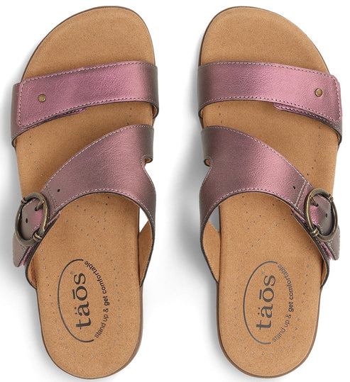 Top-down view of two mauve-colored sandals with buckle, leather straps, and Taos logo.