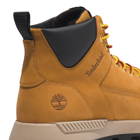 Close-up of a tan boot with yellow and red laces, a black heel, a Timberland logo on the side and a tree logo near the heel.