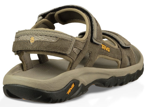 Rear view of tan sandal with black sole, and adjustable velcro straps; "Teva" visible.