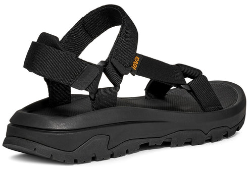 Black sandal with adjustable straps and a thick, lugged sole, 'teva' label visible.