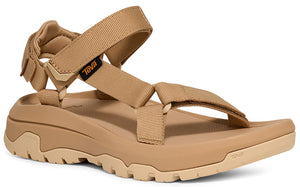 Tan sandal with adjustable straps and a thick lug sole, the word 'teva' appears on the ankle strap.