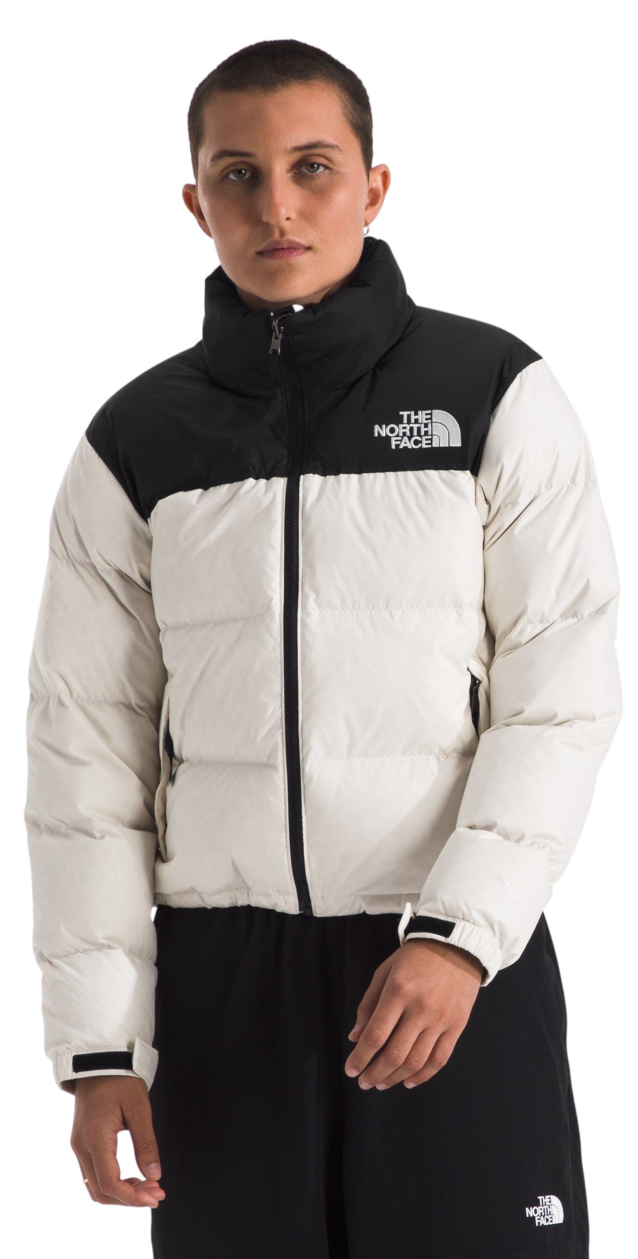 Person wearing a cream colored puffer jacket with black on the shoulders and collar with the word "THE NORTH FACE" on the right breast.