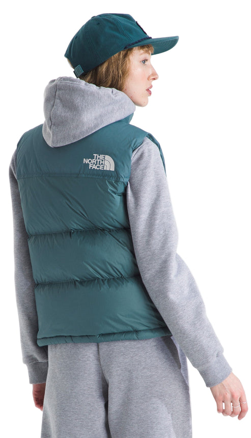 A person wearing a teal ball cap and down filled vest over a gray hooded sweatshirt and sweatpants, with logo visible on vest.