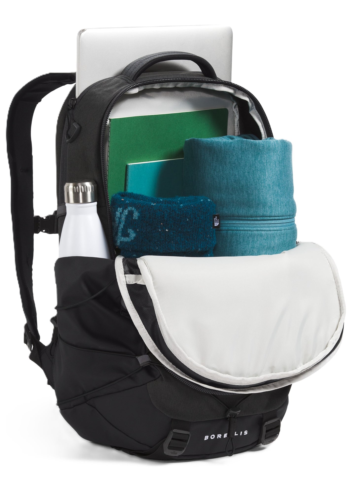 Open black backpack with white interior, showing a laptop, green books, a blue towel and a white water bottle in the side pocket. The name BOREALIS is displayed at the bottom.