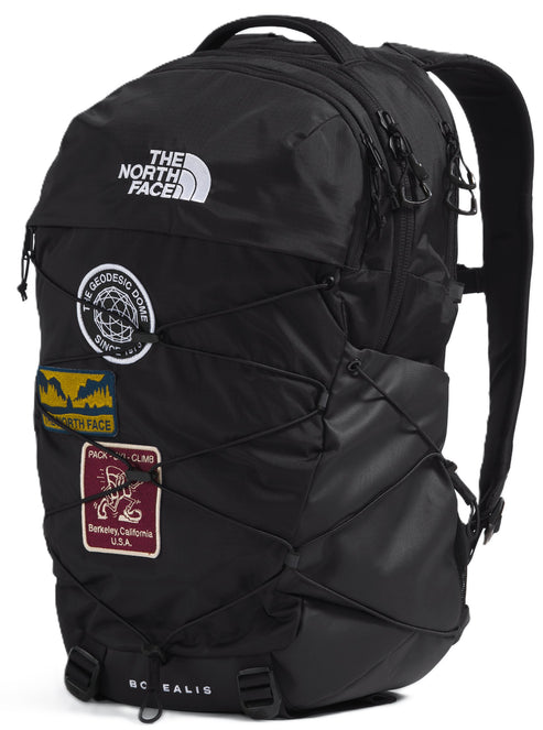Black backpack with patches and criss-crossing bungee cords on the front.