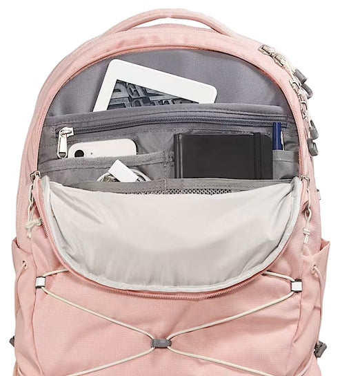 Open view of a pink backpack with multiple interior compartments holding a tablet, phone, earbuds, notepad, and pen.