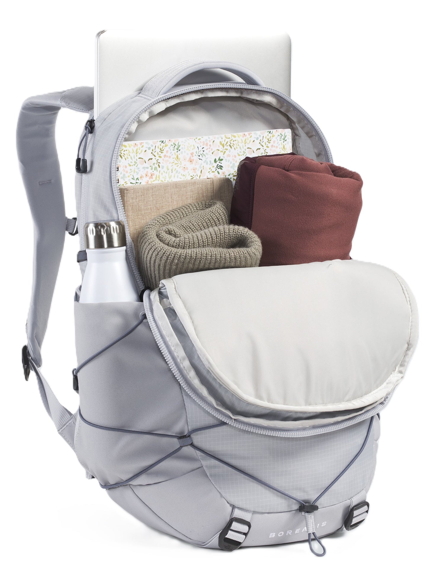 Gray backpack with water bottle in side pocket, bungee cord feature, opened to reveal clothing, book, and laptop.