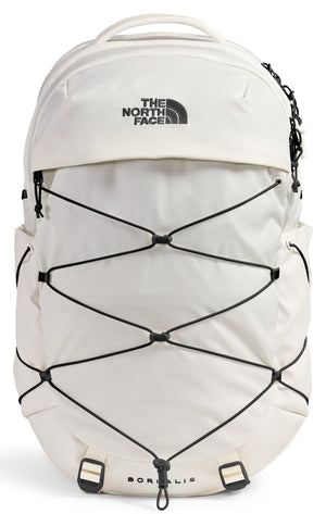 An off-white, cream-colored backpack with a black bungee cord system on the front, featuring a top handle, a zippered compartment, and text printed on the front that reads 'THE NORTH FACE' and 'BOREALIS' at the bottom.