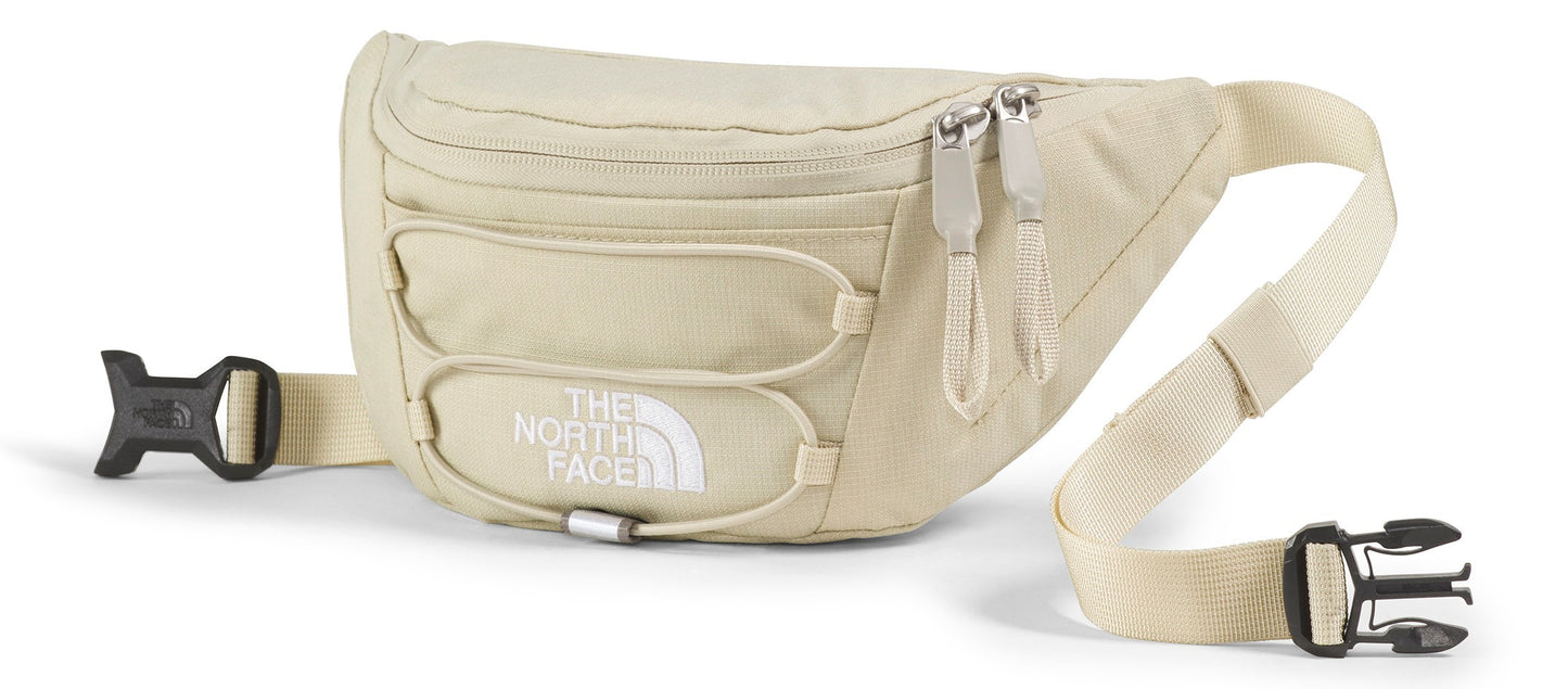 A beige fanny pack with white "THE NORTH FACE" lettering and black buckles.