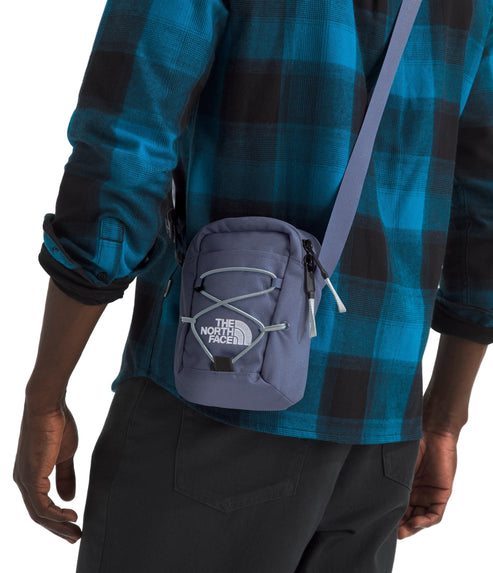 Person wearing a small blue-gray crossbody bag with white drawstring detail.