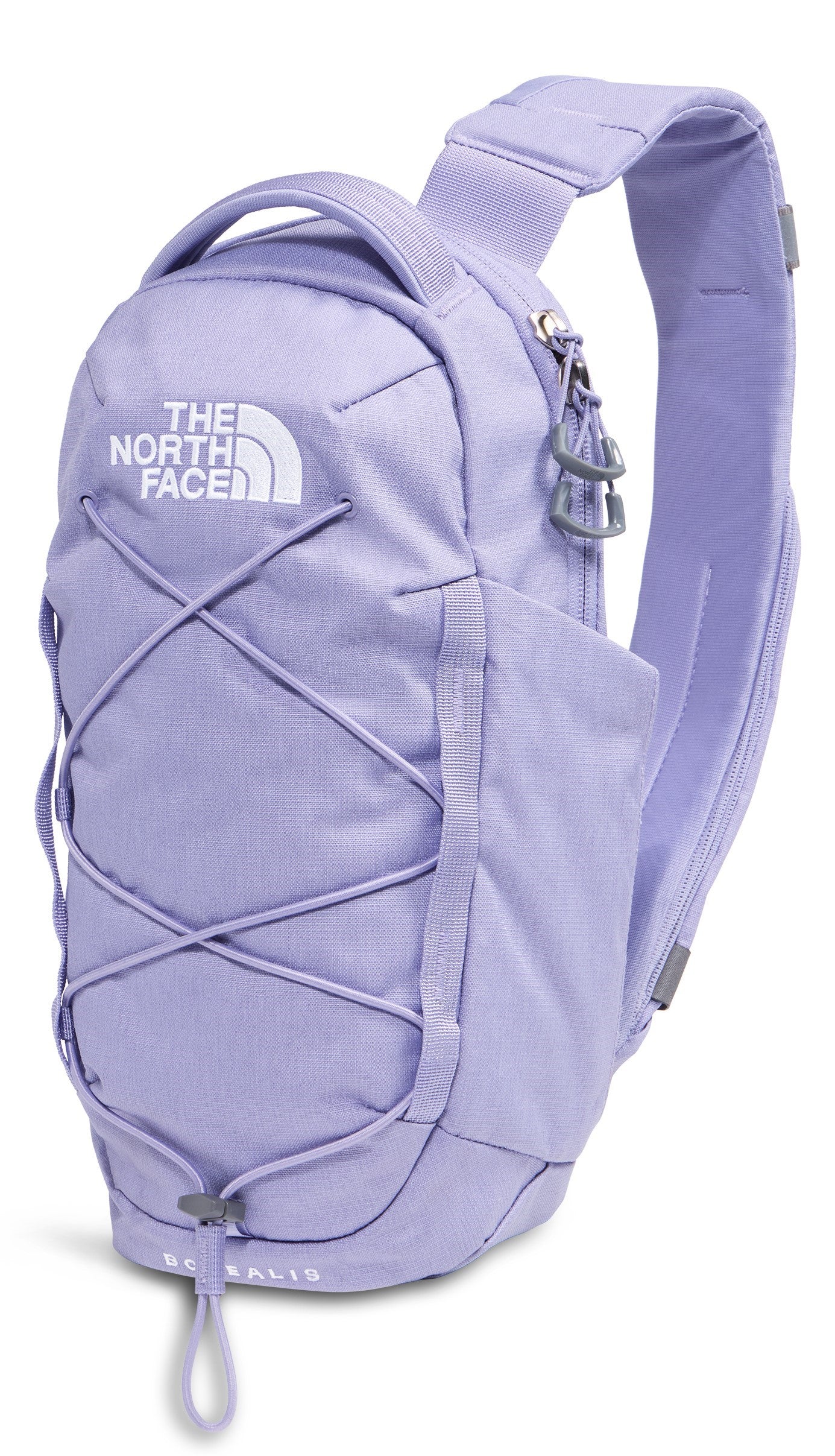 A light purple, single-strap sling backpack with a prominent top handle, a zippered main compartment, a crisscross bungee cord system on the front, and the brand name The North Face visible on the upper front.
