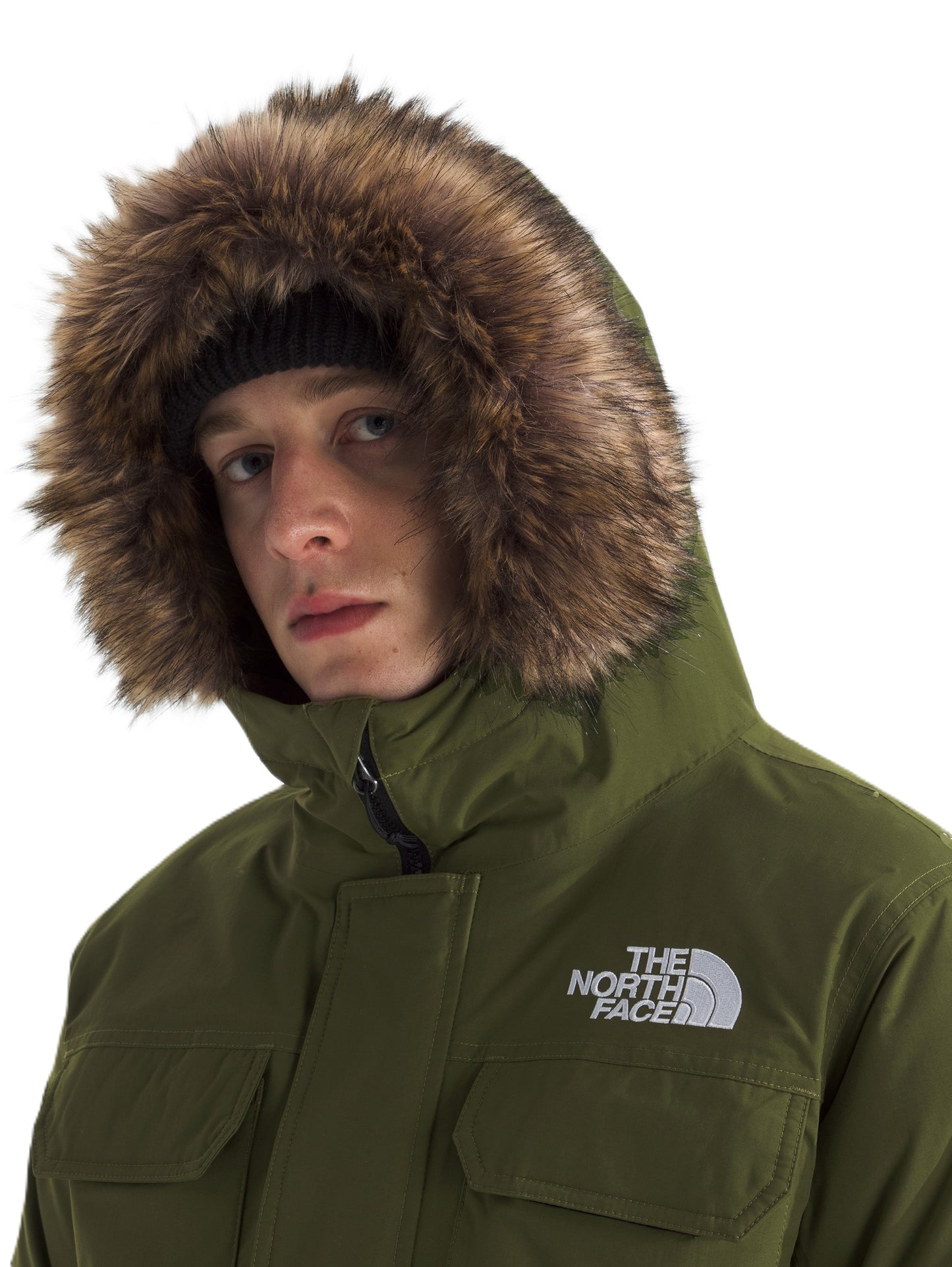 Close-up of a person wearing an olive green hooded parka with a fur-lined hood, and the text "THE NORTH FACE" printed on the garment.