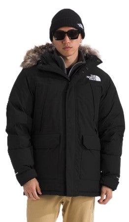 A person wearing a black beanie, sunglasses, and a black winter parka with a fur-lined hood.