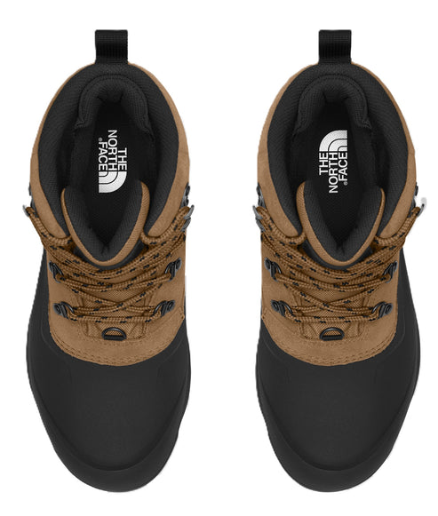 Overhead view of two hiking boots. The top is brown suede with a black interior. The bottom is black rubber with dark brown laces. The interior tongue features the text 'THE NORTH FACE'.