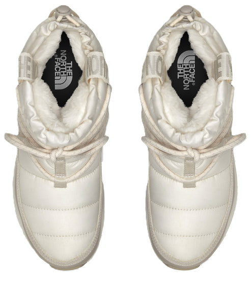 Pair of white, puffy, slipper-boots with white pull strings and white faux fur lining showing the logo THE NORTH FACE in the center of the insole.