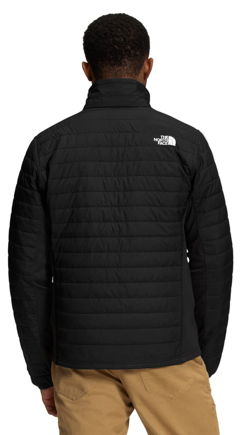 A man wearing a black puffer jacket with a white logo on the upper right.