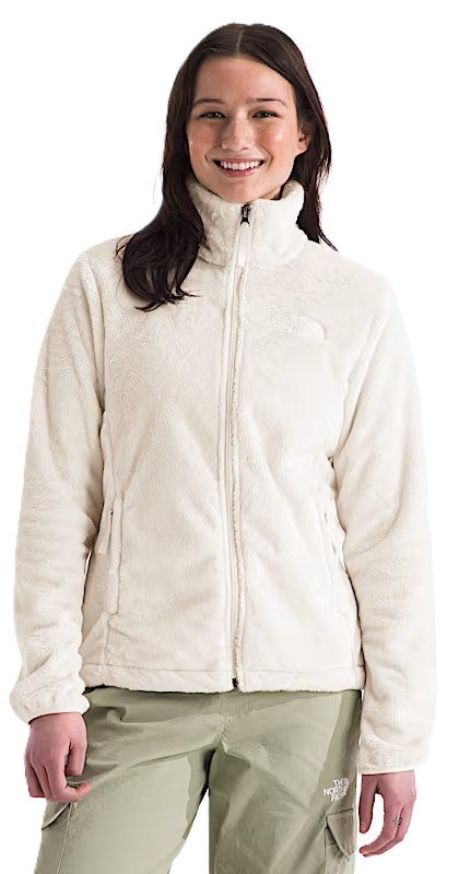 A woman is wearing a white, zippered, fuzzy fleece jacket with long sleeves and a high collar.