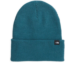 Teal knit beanie with folded brim and small black logo tag.