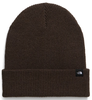 A dark brown, ribbed knit beanie with a folded cuff and a small black rectangular brand label on the right side.