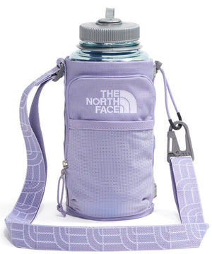 A light purple fabric water bottle holder with an adjustable, matching strap patterned with a repetitive geometric design, a grey carabiner, and a small front zipper pocket, carrying a clear water bottle with a grey cap.