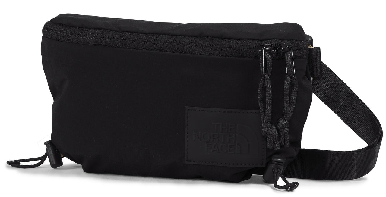 Black belt bag with zipper closure, cord details, and strap.
