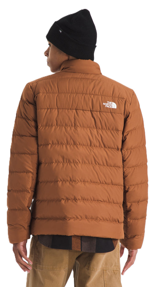 Person wearing a black beanie and a brown puffer jacket with a logo on the upper back.