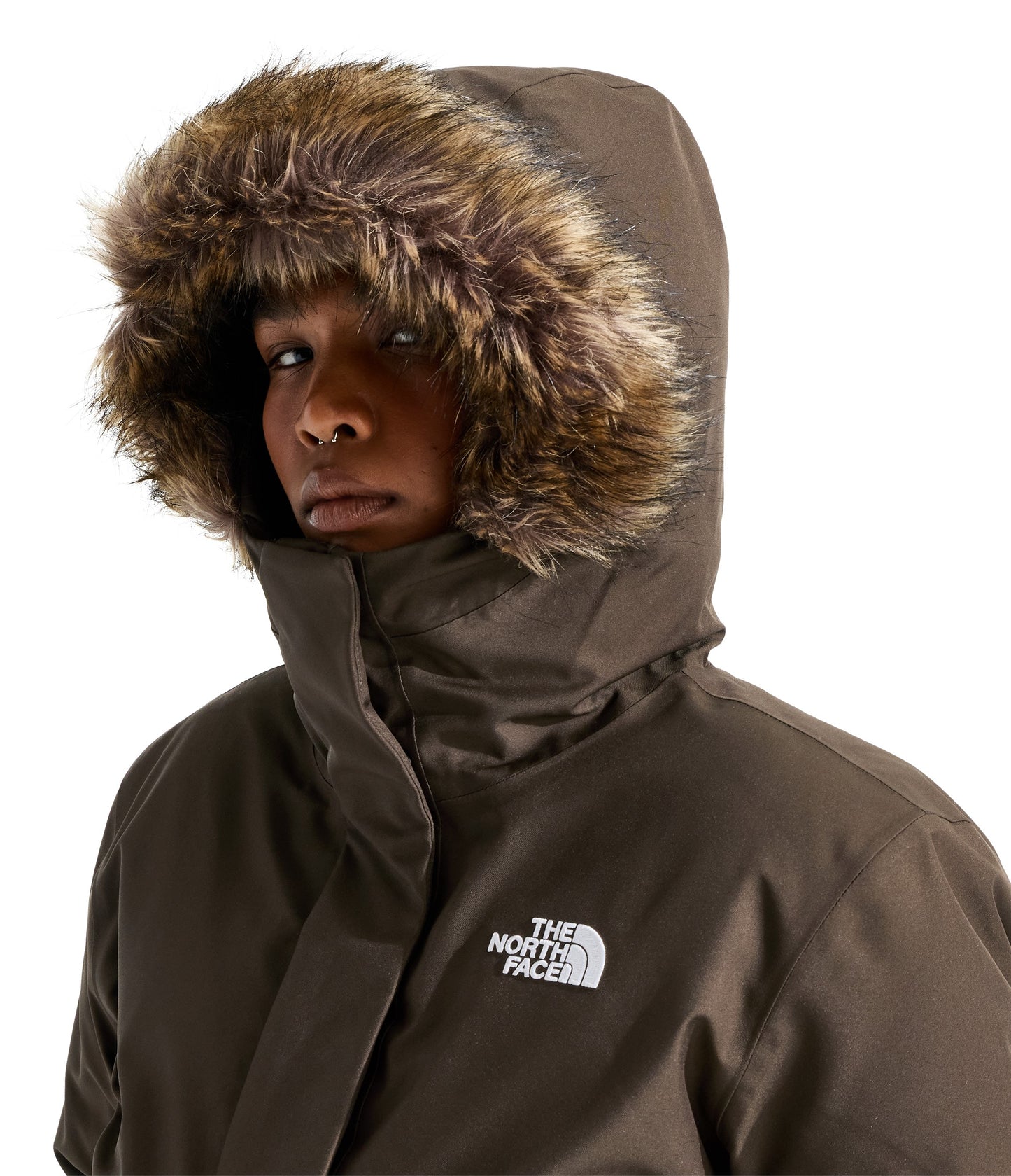 A person wearing a dark brown winter parka featuring a hood with a thick, fluffy faux-fur trim and the text THE NORTH FACE logo on the chest.