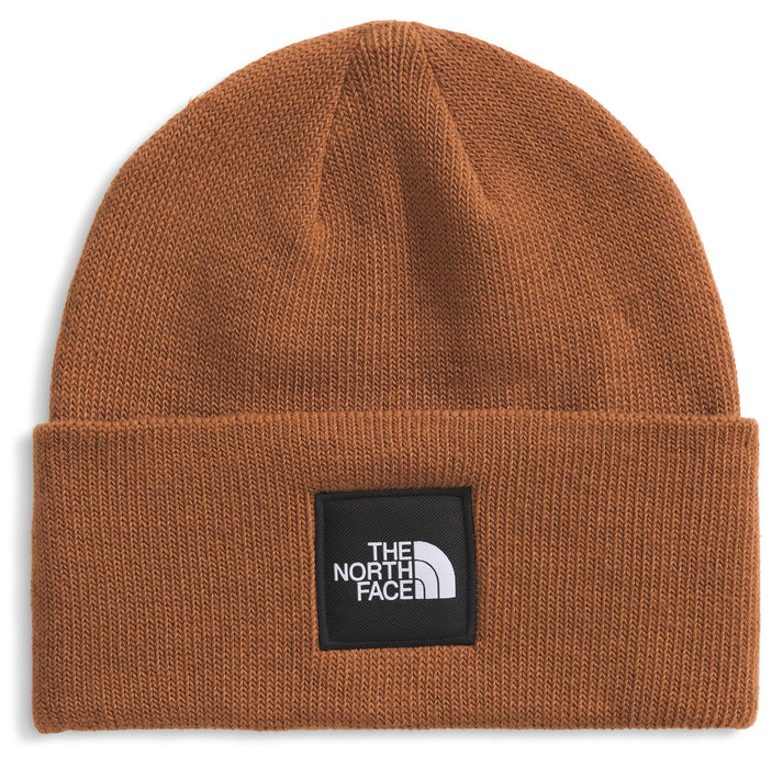 A brown beanie hat with a black square label on the front with white text.