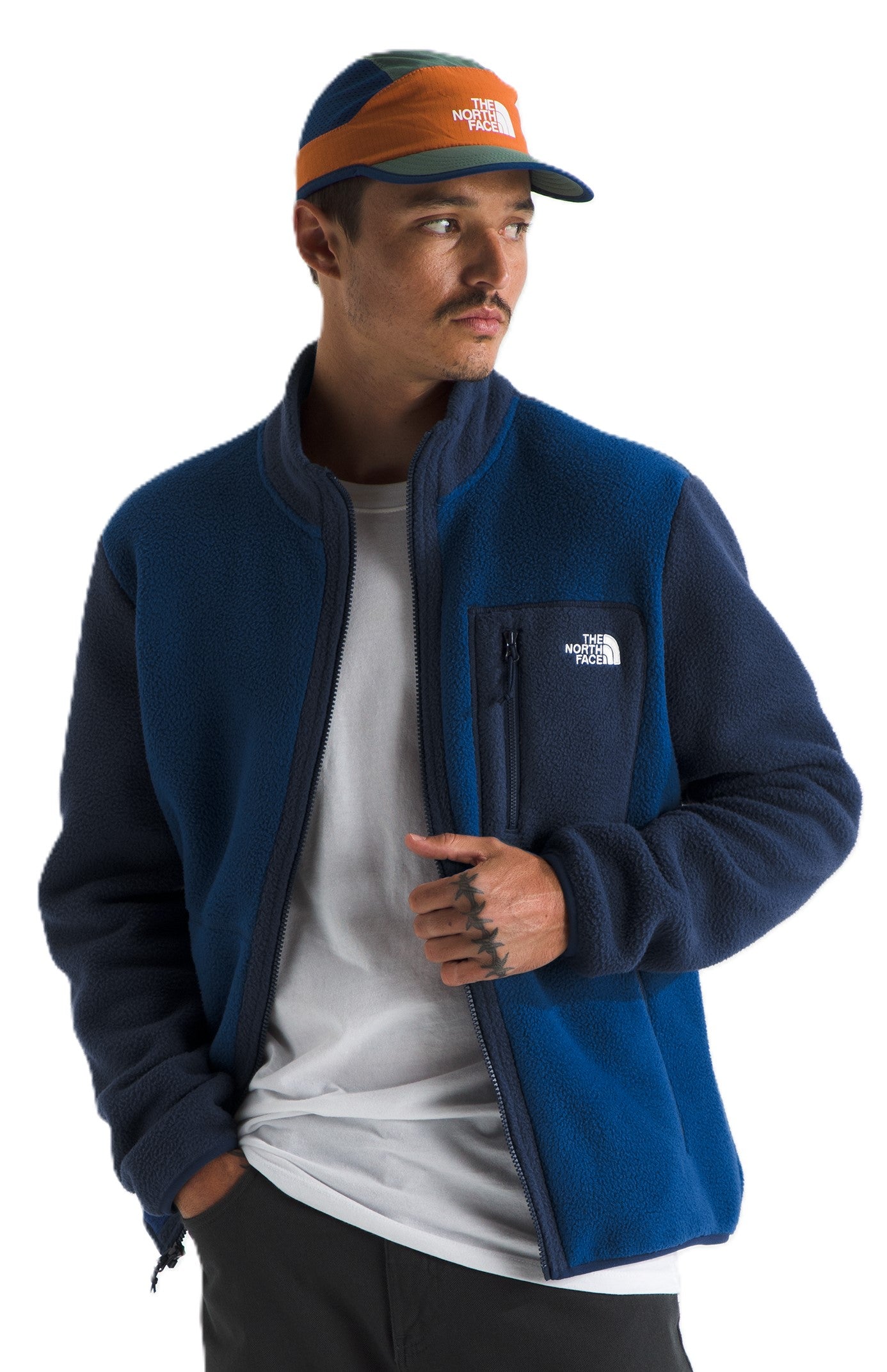 Man in a navy blue fleece jacket and a colorful baseball cap.