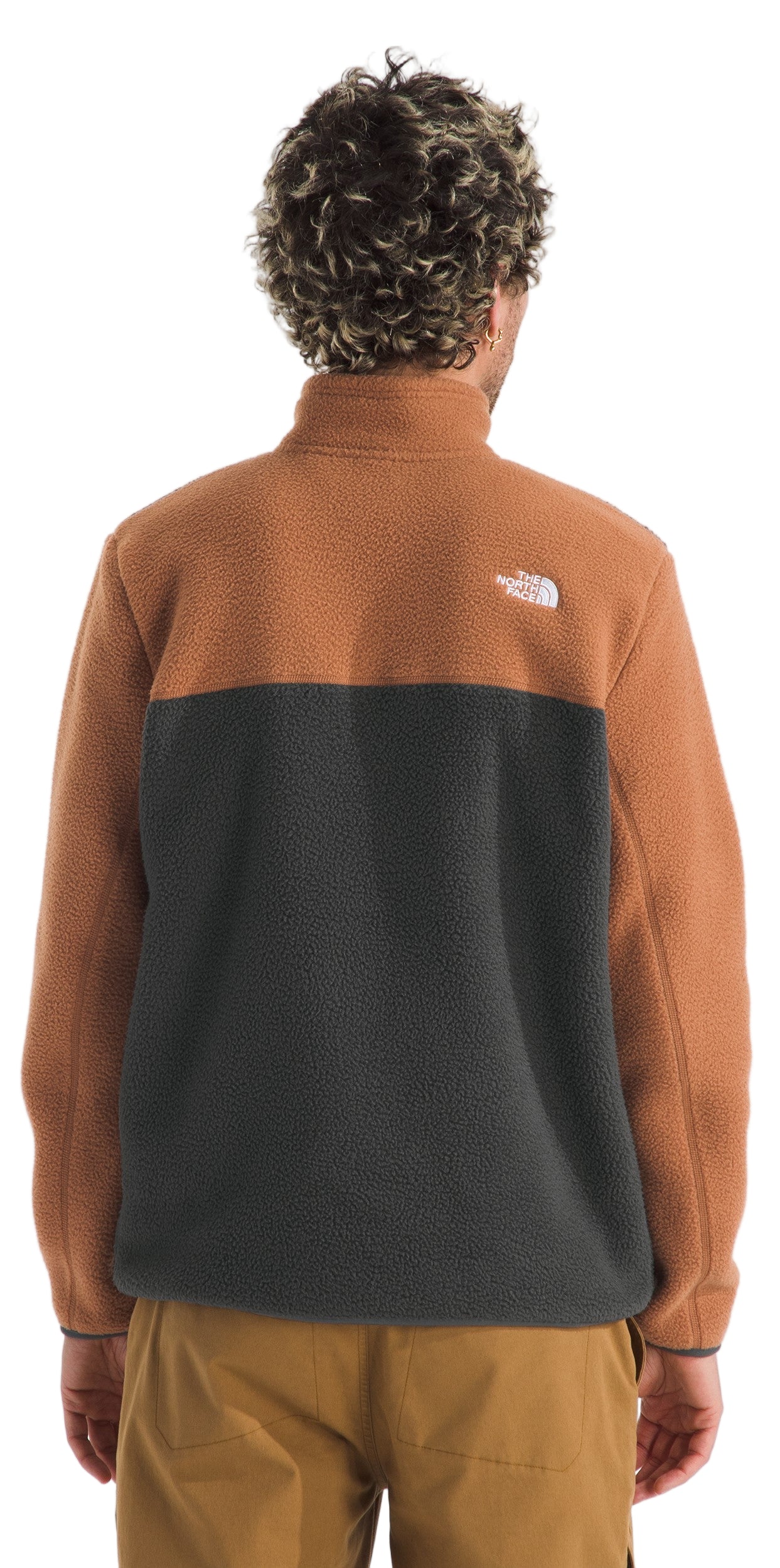 A person wearing a brown and black fleece quarter-zip pullover, seen from the back.