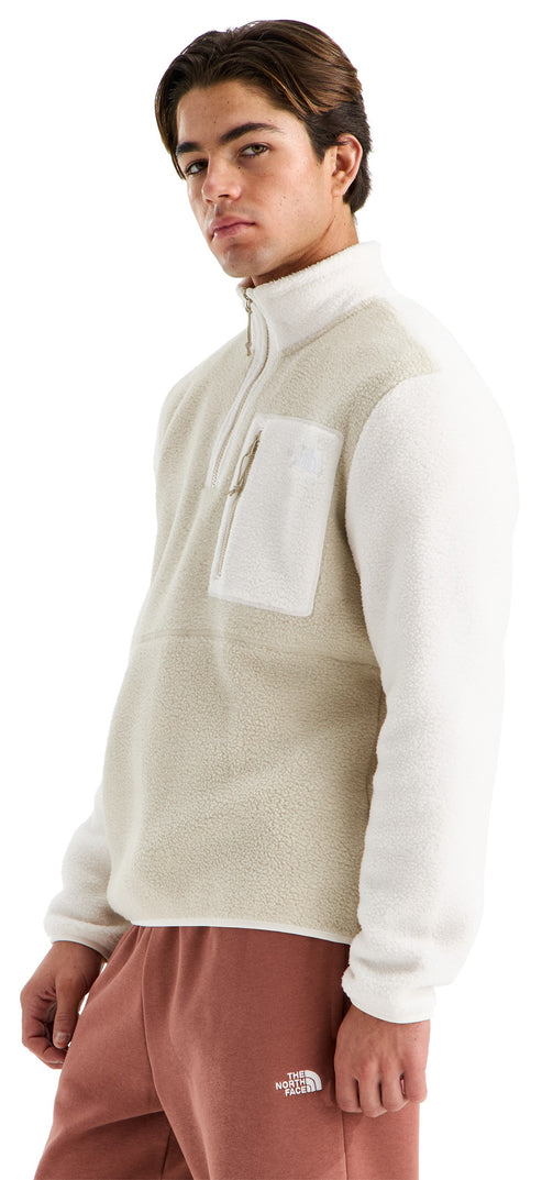 A young man posing in a cream-colored, quarter-zip fleece pullover with a light beige textured center panel and a zippered chest pocket, paired with light brown sweatpants that feature a small white logo on the left leg.