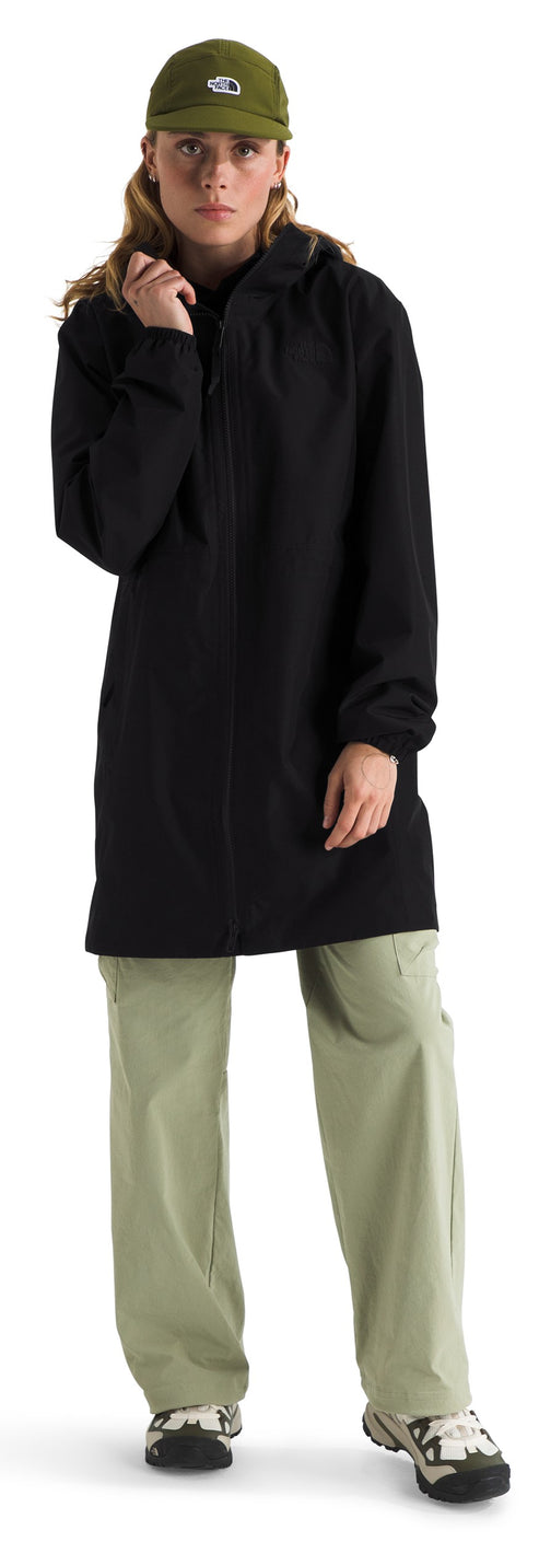 A person wearing a black jacket, olive green pants, and a matching baseball cap.