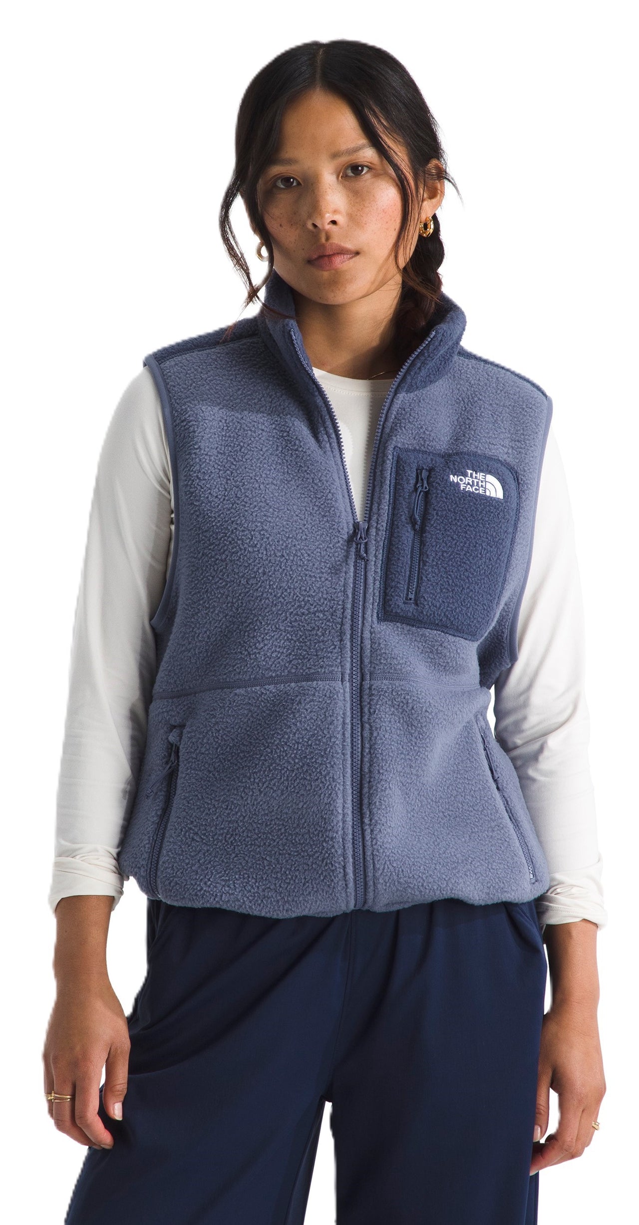 A woman wears a sleeveless, zip-up, textured fleece vest with pockets.
