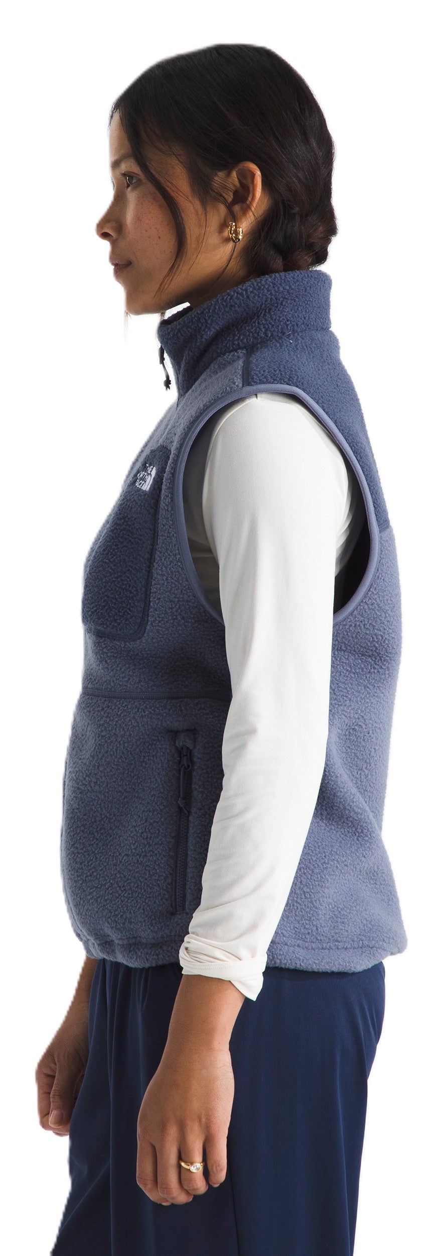 A woman wearing a blue fleece vest and a white long-sleeve shirt.