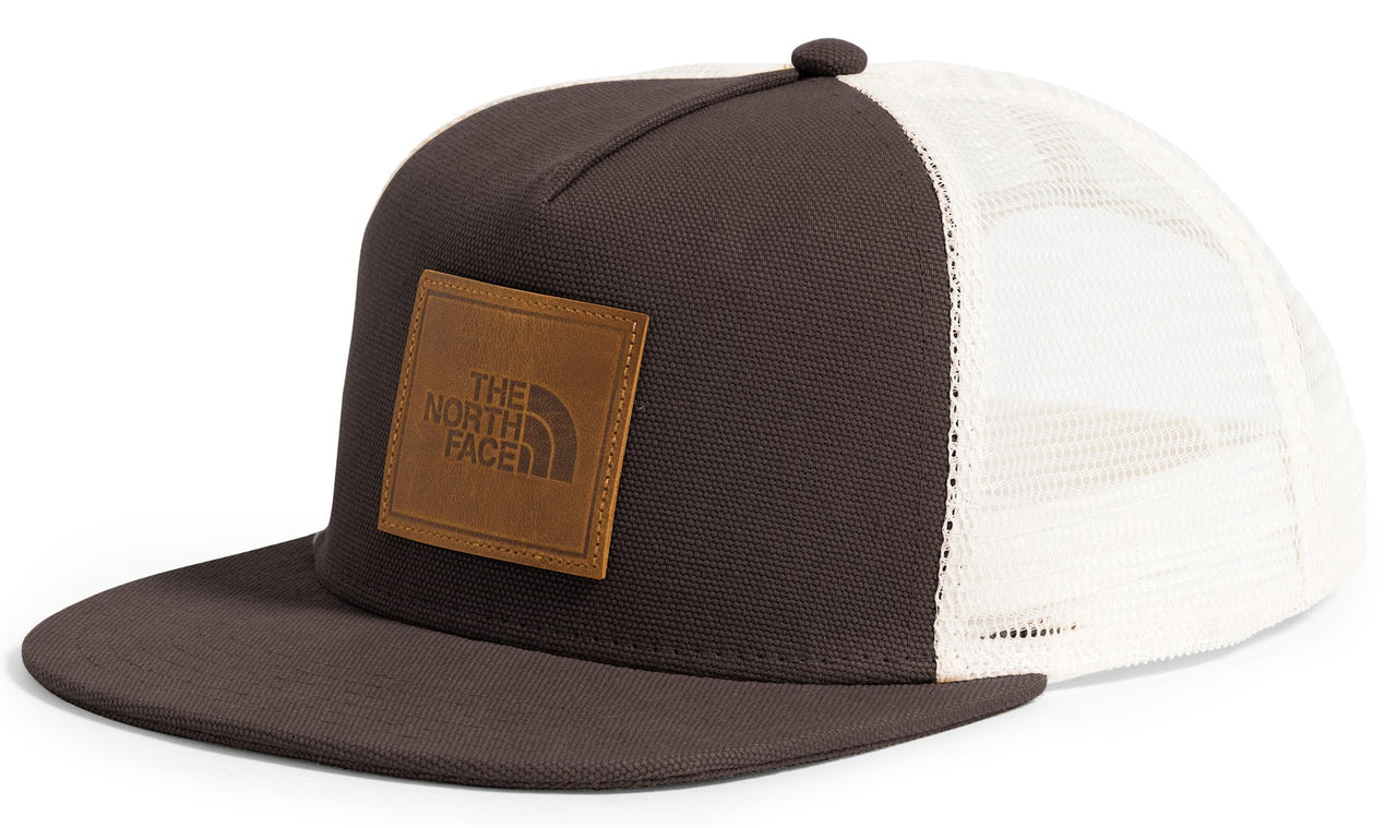 Trucker hat with dark front panel, brown square patch logo, white mesh back, and flat brim.