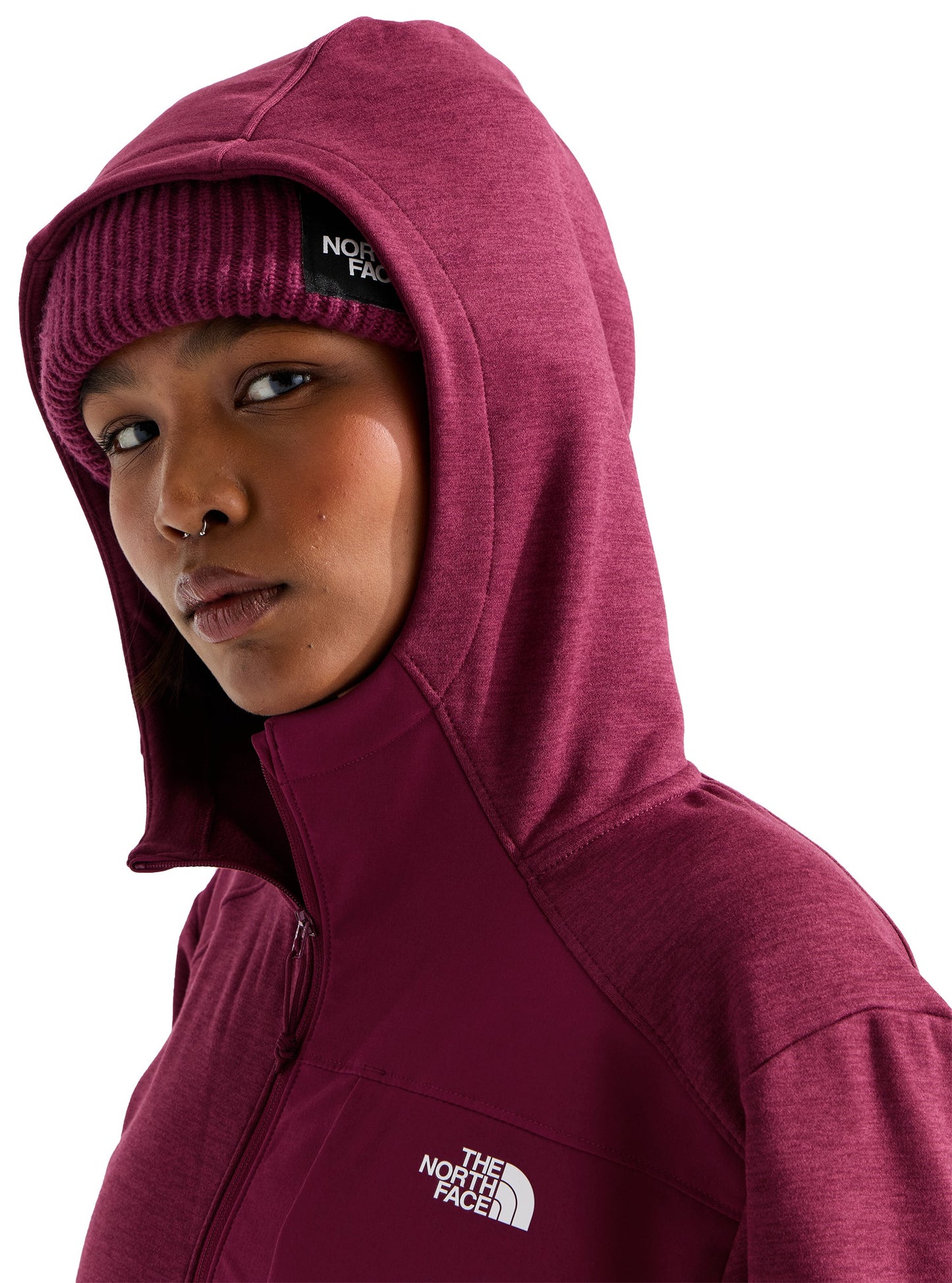 A person wearing a dark maroon hooded jacket over a matching knitted beanie, with "THE NORTH FACE" logo visible on the beanie and the chest of the jacket.