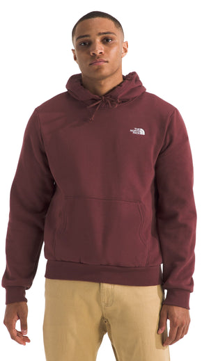 A person wearing a maroon hoodie with a logo on the chest and khaki pants.