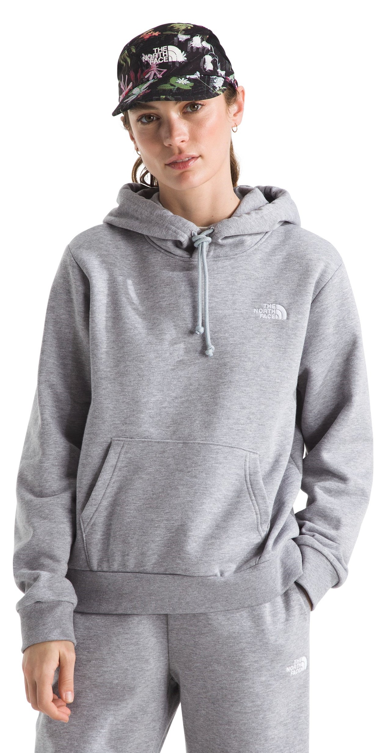 Woman wearing a gray hoodie and hat with floral print.