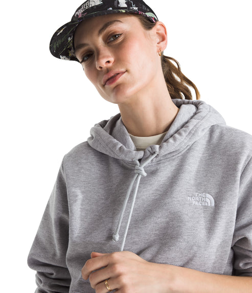 Woman wearing a gray hoodie with drawstrings and a baseball cap with a floral pattern.