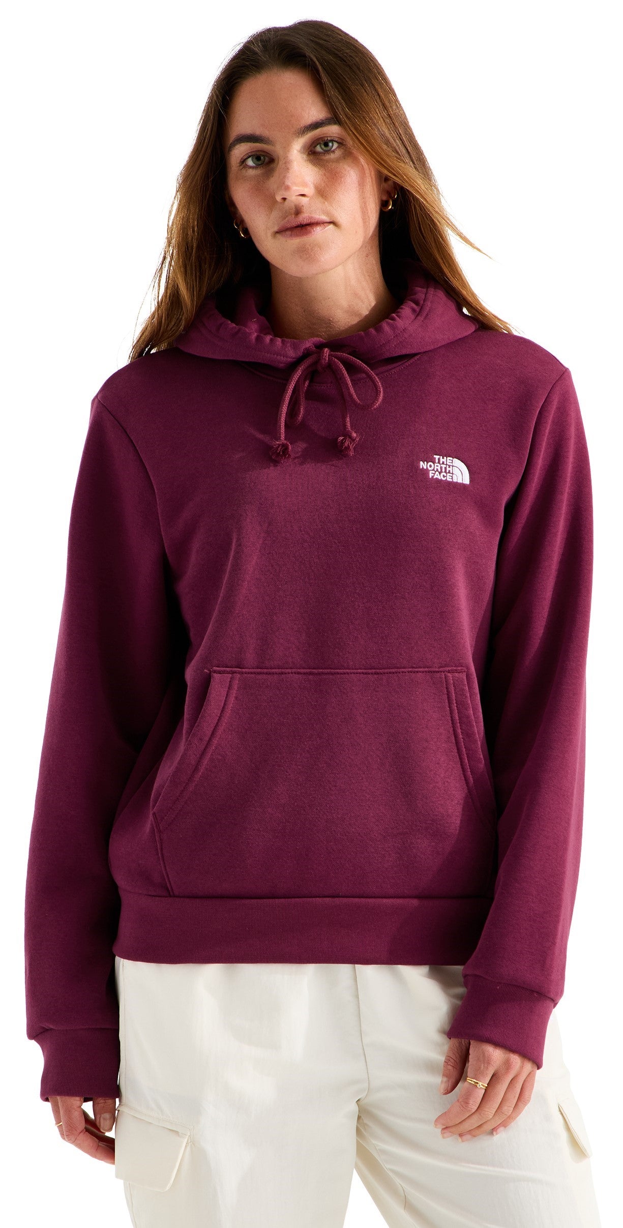 A woman wearing a long-sleeved, maroon-colored pullover hoodie with a drawstring hood and a front kangaroo pocket, featuring a small white logo on the upper left chest.