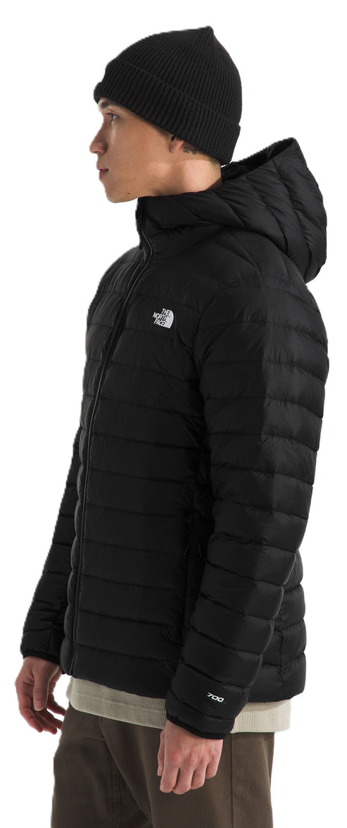 A person wearing a black quilted hooded jacket and a black beanie.