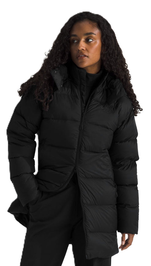 A woman with curly hair is wearing a black puffer jacket and black pants.
