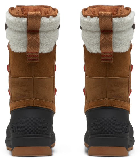 Rear view of a pair of tan and black winter boots with sherpa-lined cuffs, featuring textured black rubber lower shells and vertical pull tabs on the back.