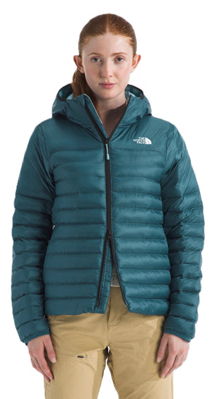 A woman wearing a green down jacket with a hood and a zipper.